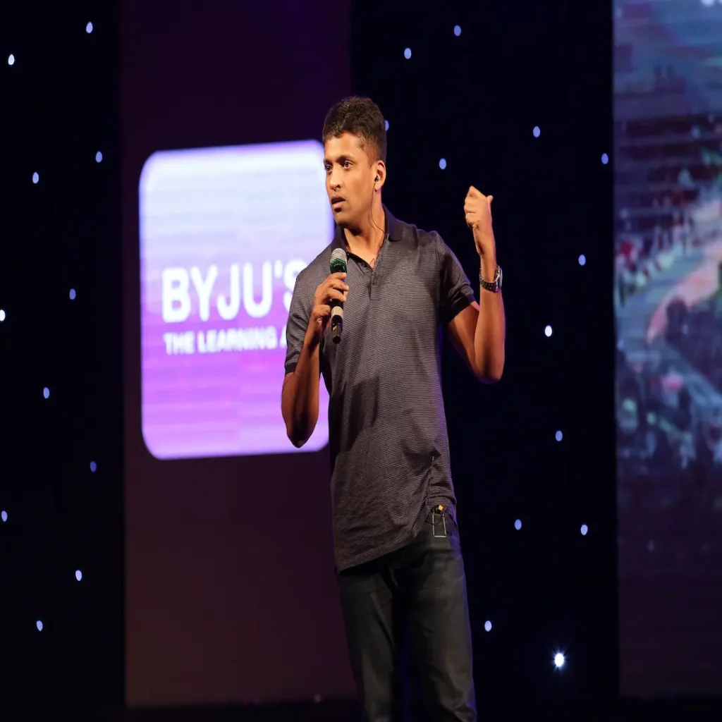 Byju Raveendran, founder and CEO of Byju's, speaking into a microphone on stage during a presentation, featured in a corporate case study about the edtech company's rise and insolvency.